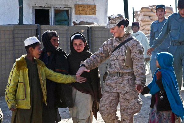 Petty Officer 2nd Class Kimberley Ryan holds hands with Afghan children as they walk to the local children's shura in Afghanistan's Helmand province, 2012. Photo by Cpl. Ed Galo, U.S. Marine Corps, public domain via Wikimedia Commons